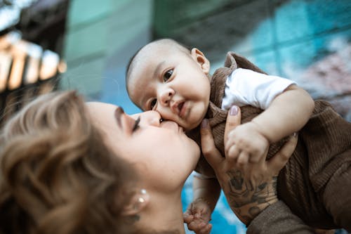 Close Up Photo of Woman Kissing a Baby Boy