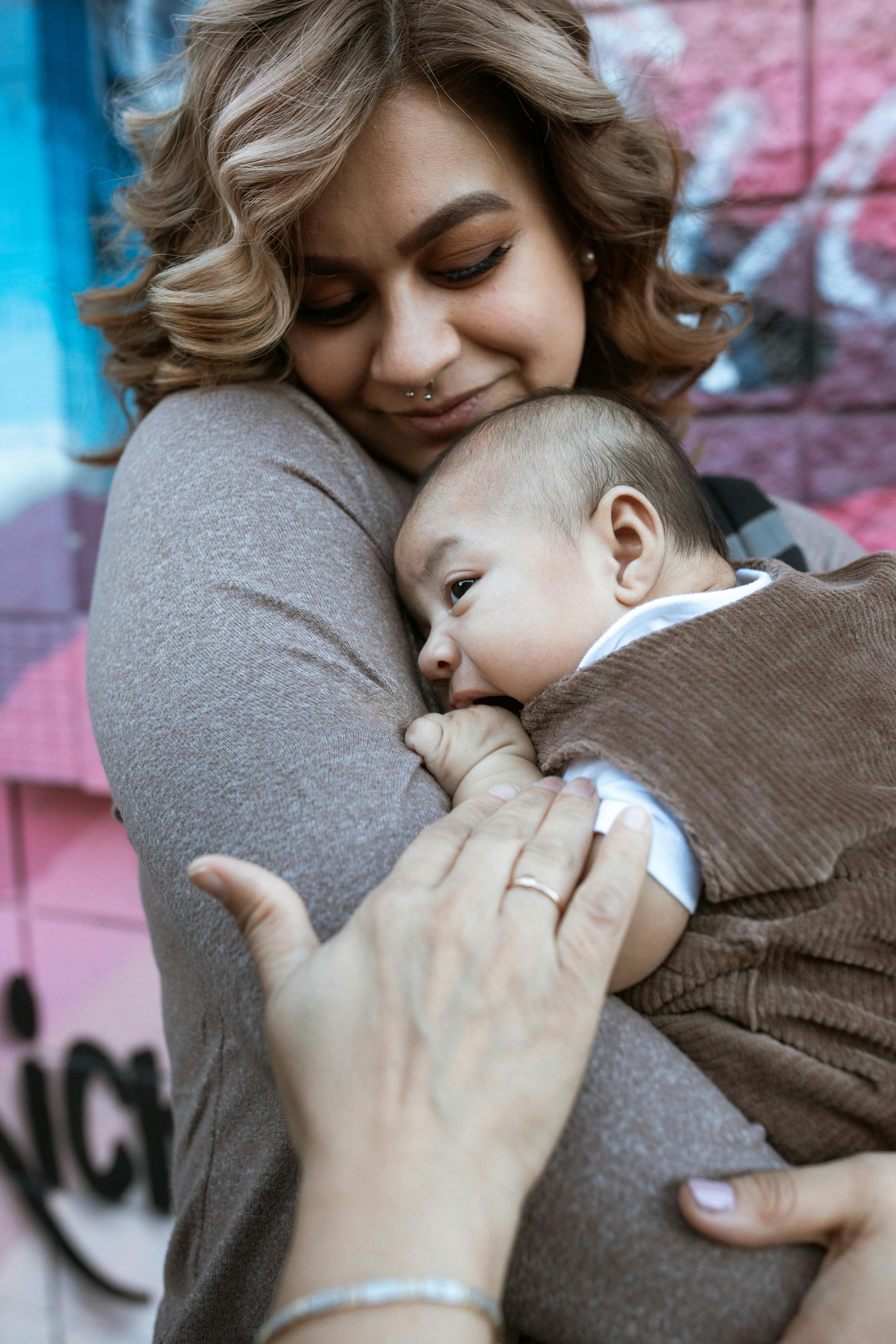 woman in gray long sleeve shirt carrying a baby