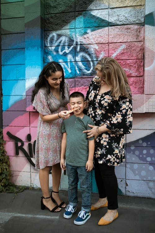 A Boy Standing Between Two Women