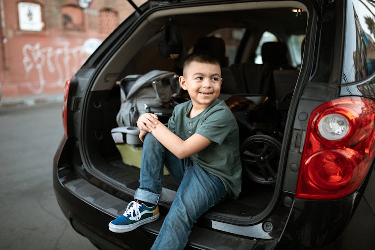 A Boy Sitting In A Car Looking Over His Shoulder