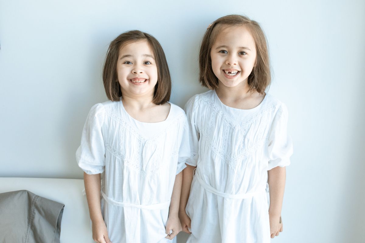 Two girls in matching white dresses indoors