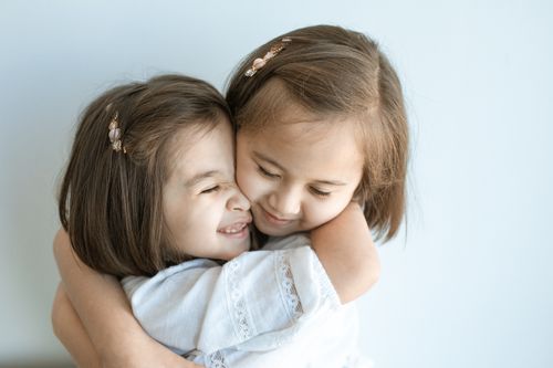 Free Two young girls embracing warmly, displaying sibling love and happiness against a plain background. Stock Photo