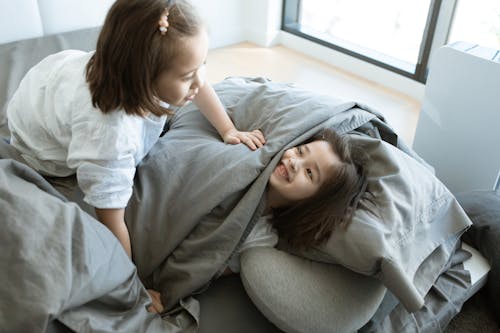 Free Two Girls Playing With Pillows and Blankets in Bed Stock Photo