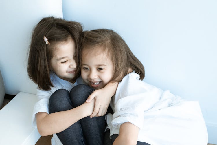 Two Girls Wearing White Top And Leggings Hugging Each Other