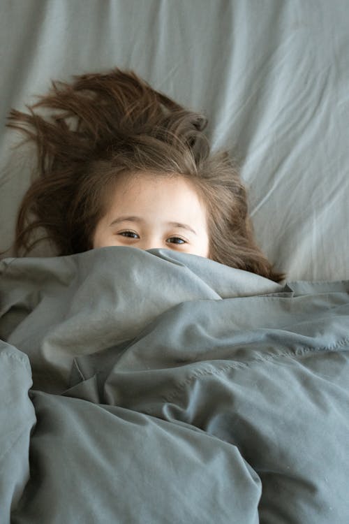 Free Girl Lying on the Bed Covered with Blanket Stock Photo