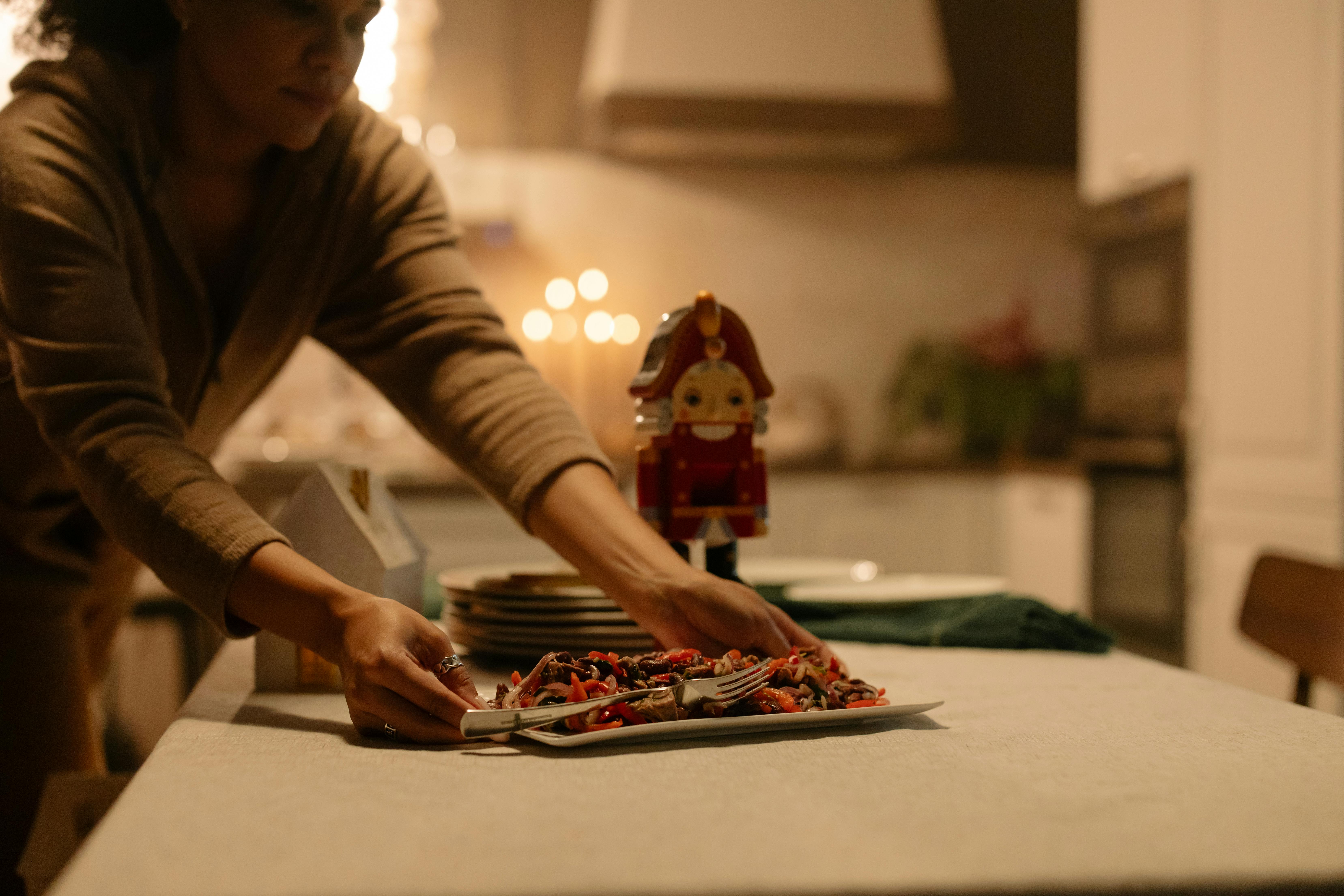 Person setting the dinner table with plates and glasses