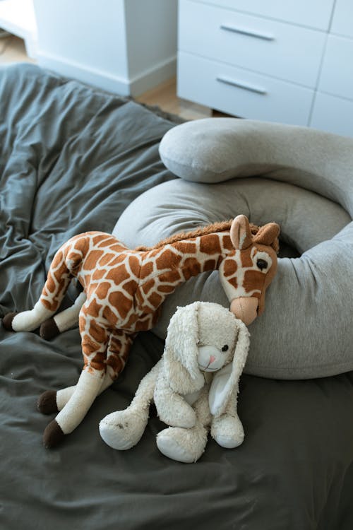 灰色沙发上的棕色和白色长颈鹿毛绒玩具