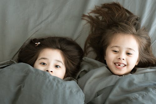 Free Girls Lying on Bed Under a Blanket Stock Photo