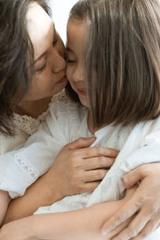 A mother lovingly embraces her daughter, showcasing a tender moment of affection and warmth.