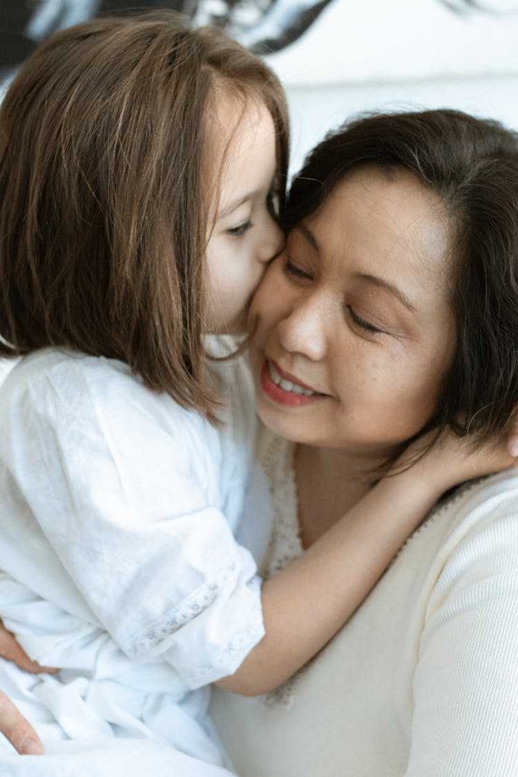 A Girl Kissing The Woman On The Cheek 