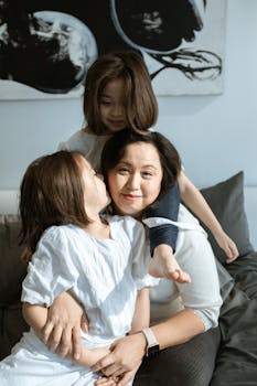 Asian mother with her two daughters enjoying a tender moment indoors, showcasing love and affection.