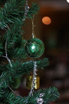Close-up of a green bauble on a Christmas tree, creating a festive mood.