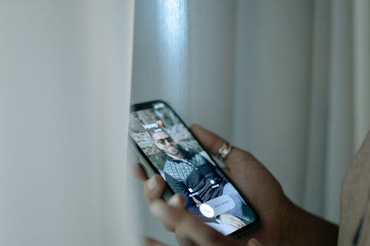 A hand holding a smartphone showing an incoming call notification with a photo of a man on the screen.
