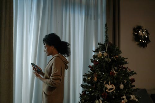 Woman in Brown Sweater Standing Beside Green Christmas Tree