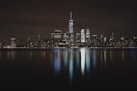 迷人的纽约市天际线夜景倒映在海滨，展现出城市的建筑之美