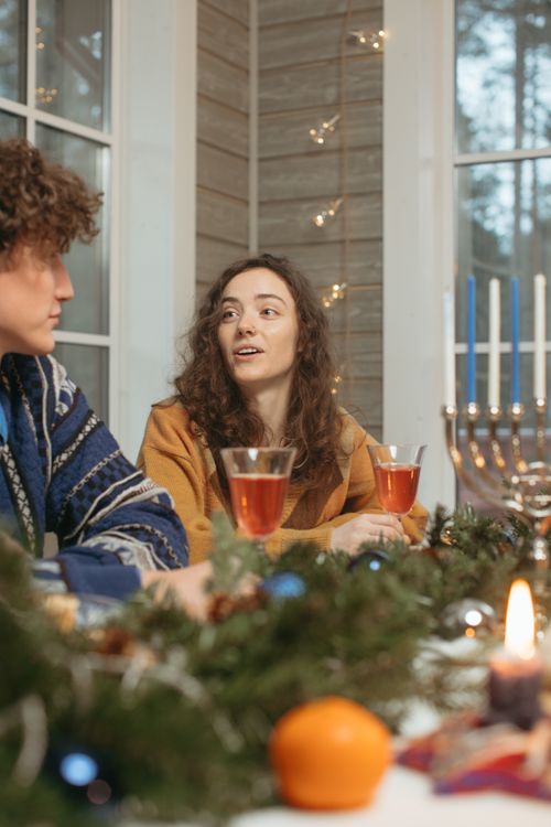 Free Two friends enjoying a festive Hanukkah celebration indoors with candles and decorations. Stock Photo