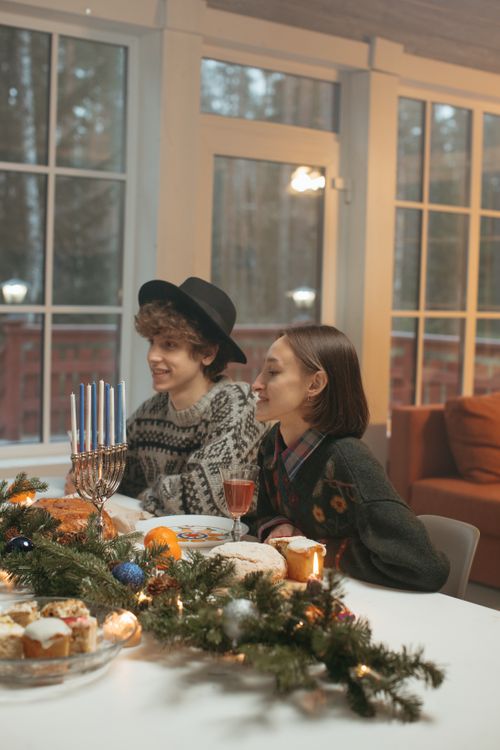 Free Two friends enjoying a warm Hanukkah dinner indoors with festive decorations. Stock Photo