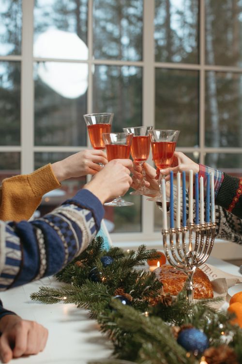 Free Friends toasting with drinks at a cozy holiday gathering with candles and decorations. Stock Photo