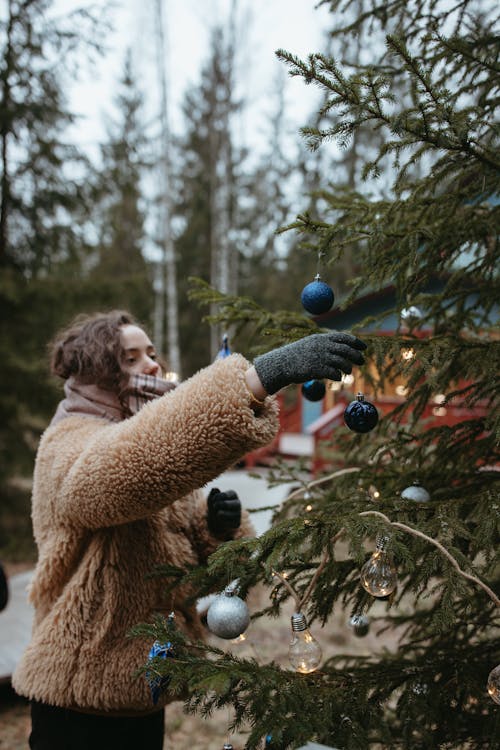 Woman in Brown Fur Coat Holding Blue and Green Christmas Baubles