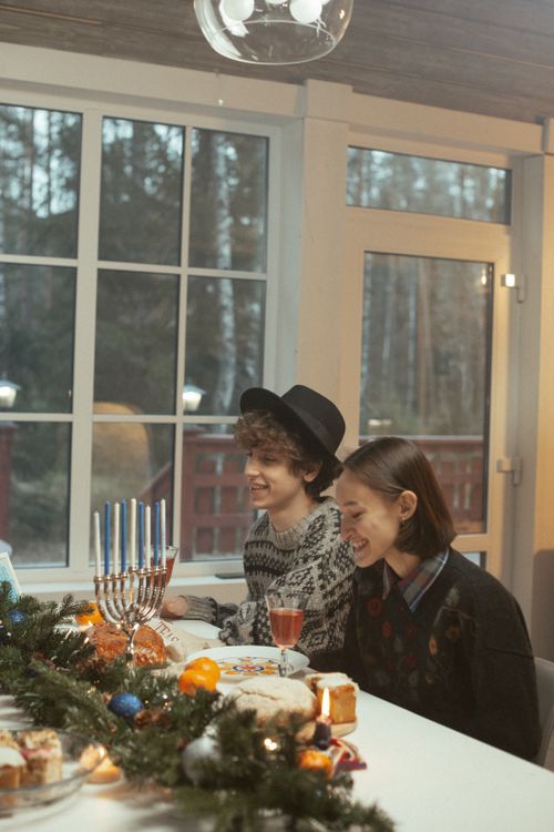Free A warm, intimate Hanukkah dinner party with friends enjoying food and decorations indoors. Stock Photo