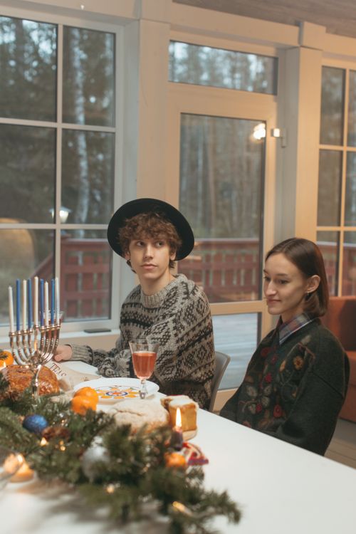 Free Intimate indoor Hanukkah celebration with menorah, candles, and festive dinner table setting. Stock Photo