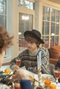 Woman in Black Hat and Brown Scarf Sitting on Chair