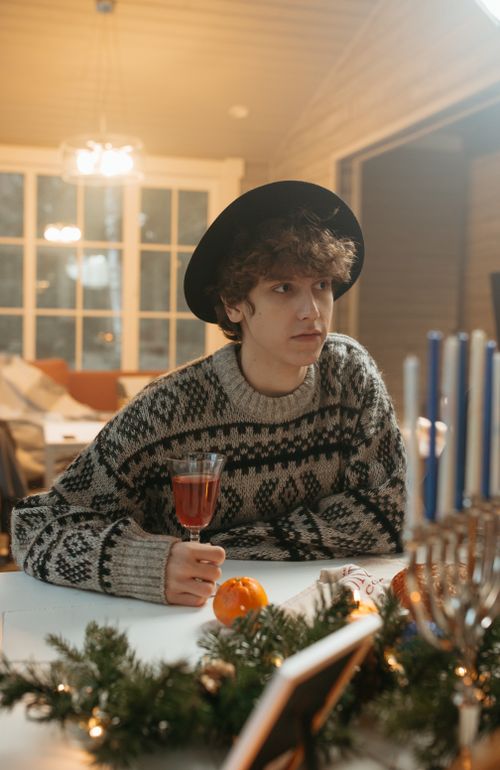 Free Young man in cozy holiday sweater enjoying a festive indoor gathering with decorations. Stock Photo