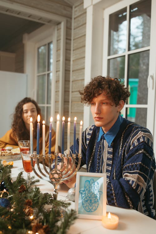 Man in Blue Sweater Looking at the Candles