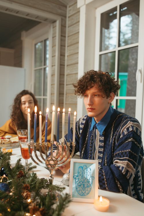 Free Young adults sitting behind a menorah during a warm Hanukkah celebration indoors. Stock Photo