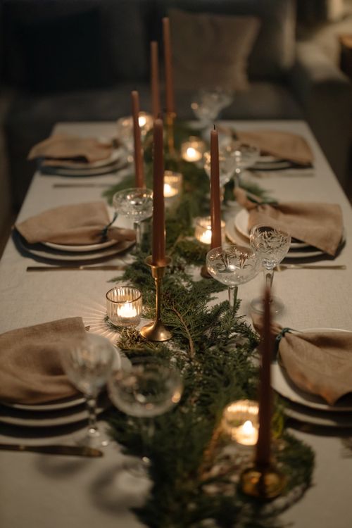 Free Beautifully set dining table with candles and greenery for a cozy holiday dinner. Stock Photo