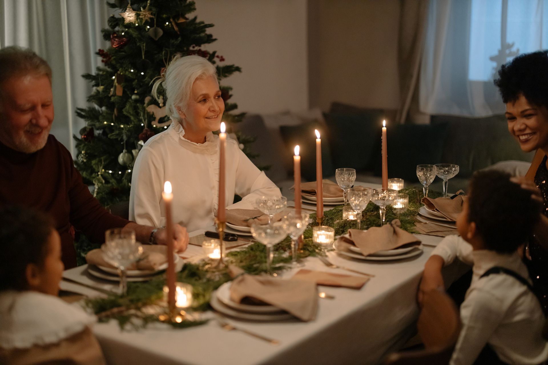 An Elderly Woman Smiling at a Dining Table with Her Family