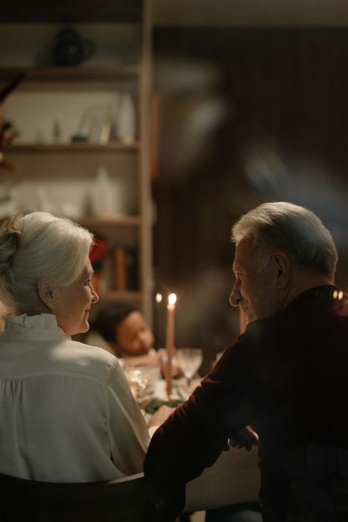 Free Senior couple enjoying a warm family dinner by candlelight, creating a cozy and intimate atmosphere. Stock Photo