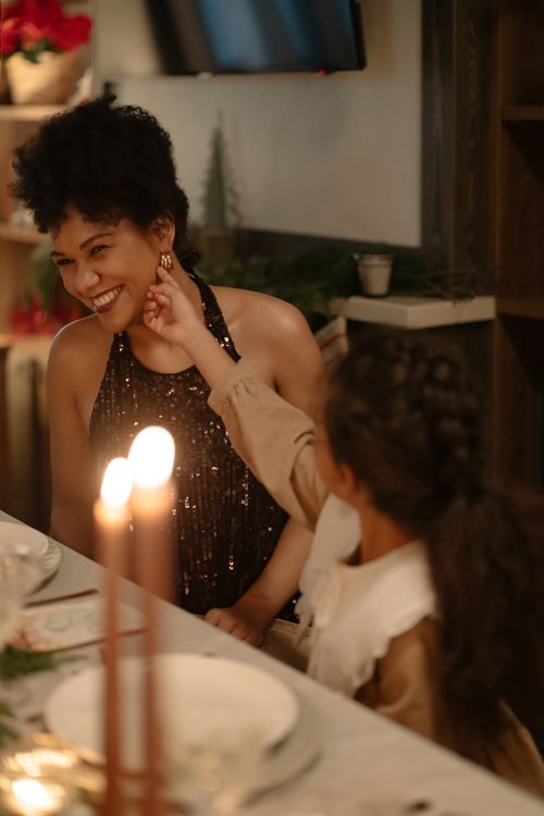 Free Mother and daughter sharing a playful moment during a festive dinner at home. Stock Photo
