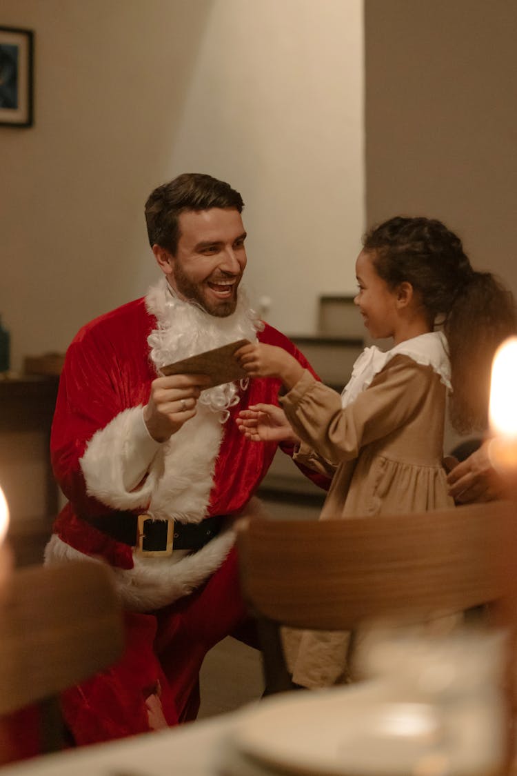 Man In Santa Clothes Giving An Envelope To A Kid