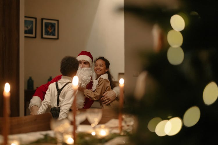 Kids Hugging Their Father Dressed As Santa Claus At Home