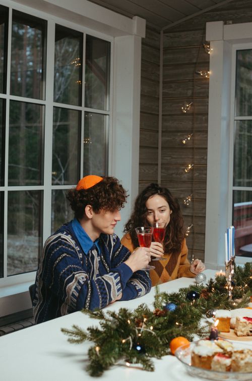 Free A couple enjoys drinks in a warmly decorated room, celebrating Hanukkah. Stock Photo