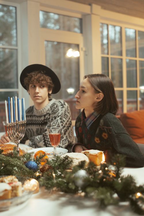 Free Two people enjoying a festive Hanukkah celebration indoors, adorned with decorations and a menorah. Stock Photo