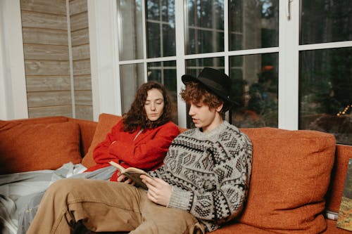 Man and Woman Sitting on Orange Sofa