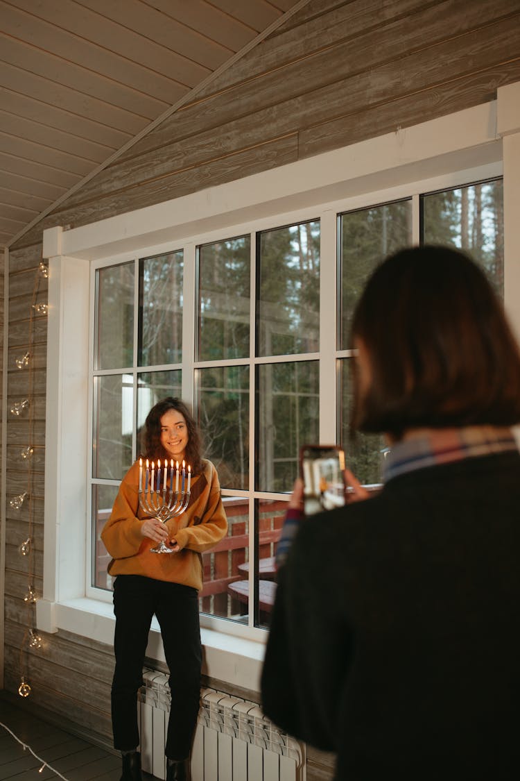 Woman Holding A Menorah Standing By The Window