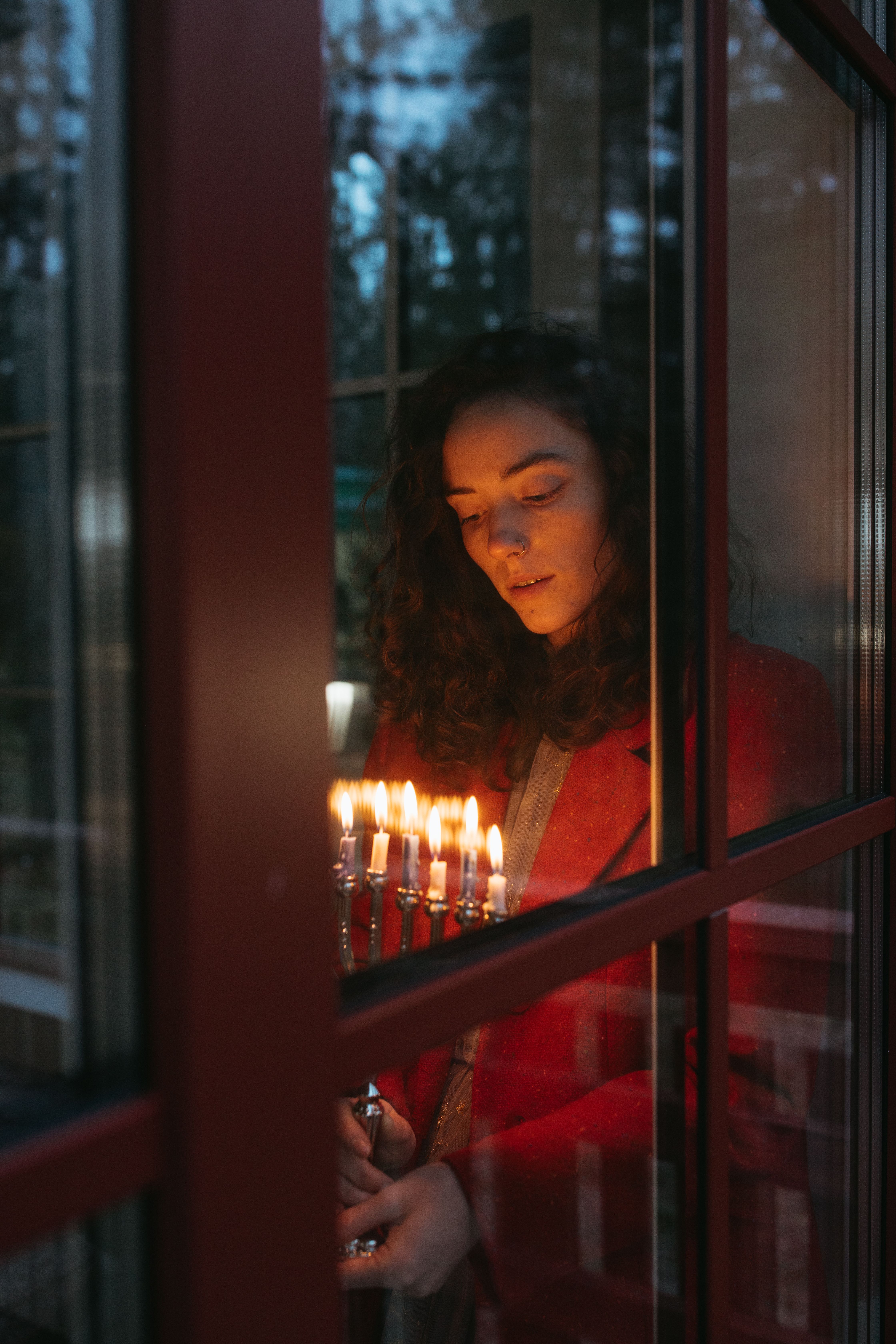 Amber glass candle lit beside a window