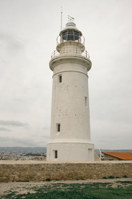 A striking white lighthouse stands against a cloudy sky in Paphos, offering a classic coastal landmark view.