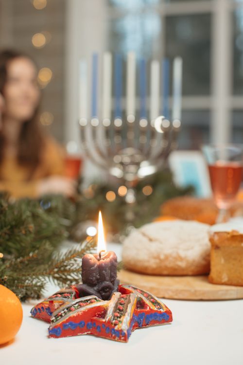 Free A cozy indoor holiday setting with a menorah, candle, and festive food on a dining table. Stock Photo