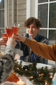 Young adults enjoying a festive holiday toast indoors, creating a warm celebration atmosphere.