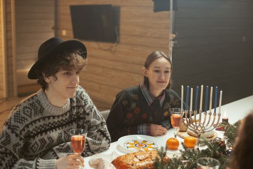 Free Celebratory Hanukkah dinner featuring a menorah, festive atmosphere, and friends sharing drinks. Stock Photo