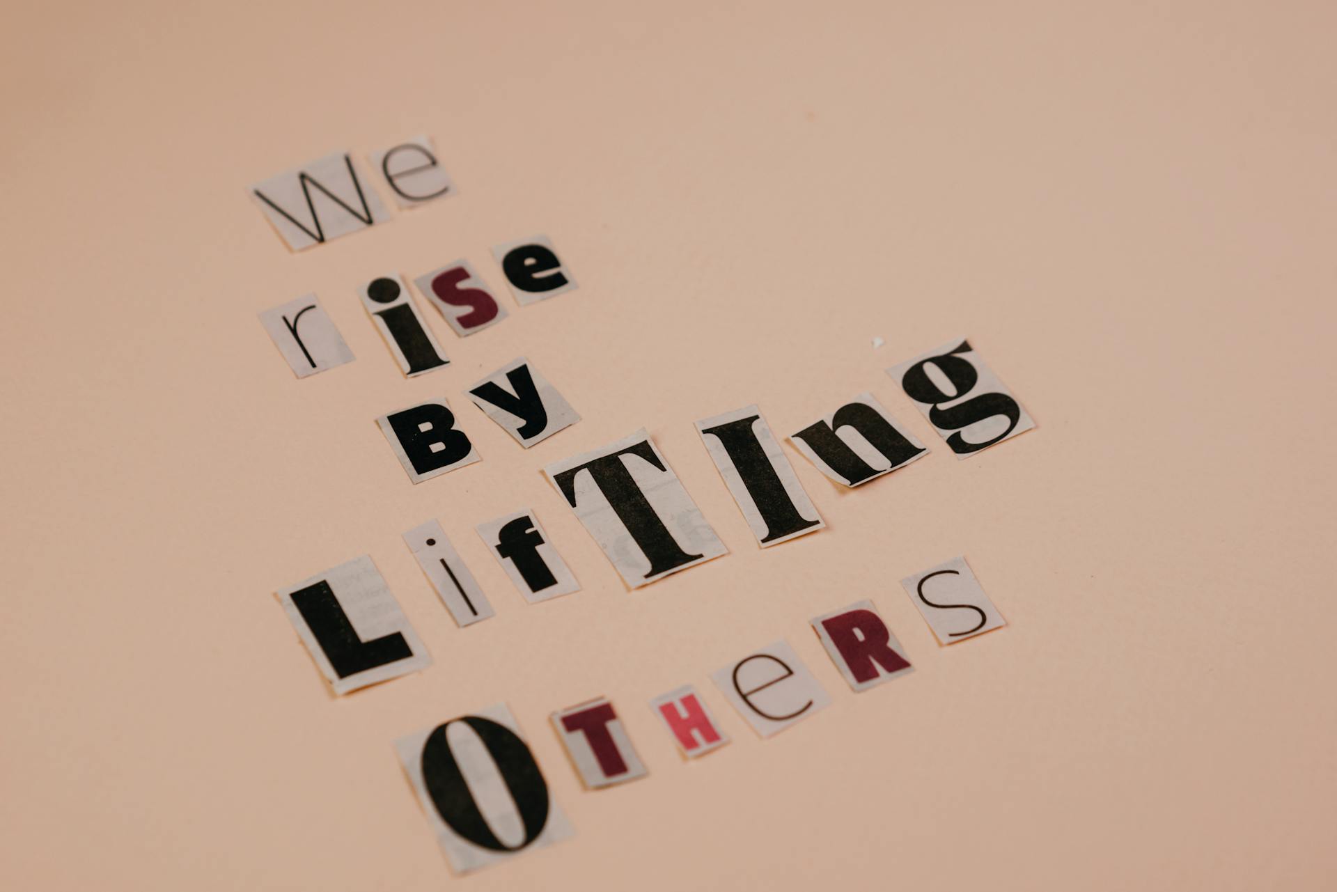 Cutout letters forming an inspirational quote on a beige background, encouraging positivity.