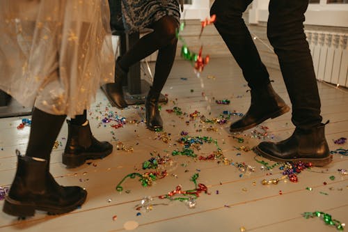 People in Black Leather Boots Standing on Floor With Confetti 