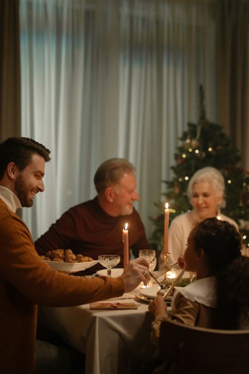 Free A family enjoying a warm Christmas dinner with candlelight and festive ambiance. Stock Photo