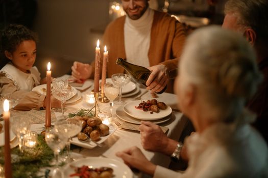 A warm and festive family dinner setting with candles and wine. Diversity and togetherness at holiday gathering.