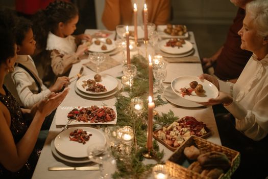 A diverse family enjoying a holiday dinner with candles and festive setting.