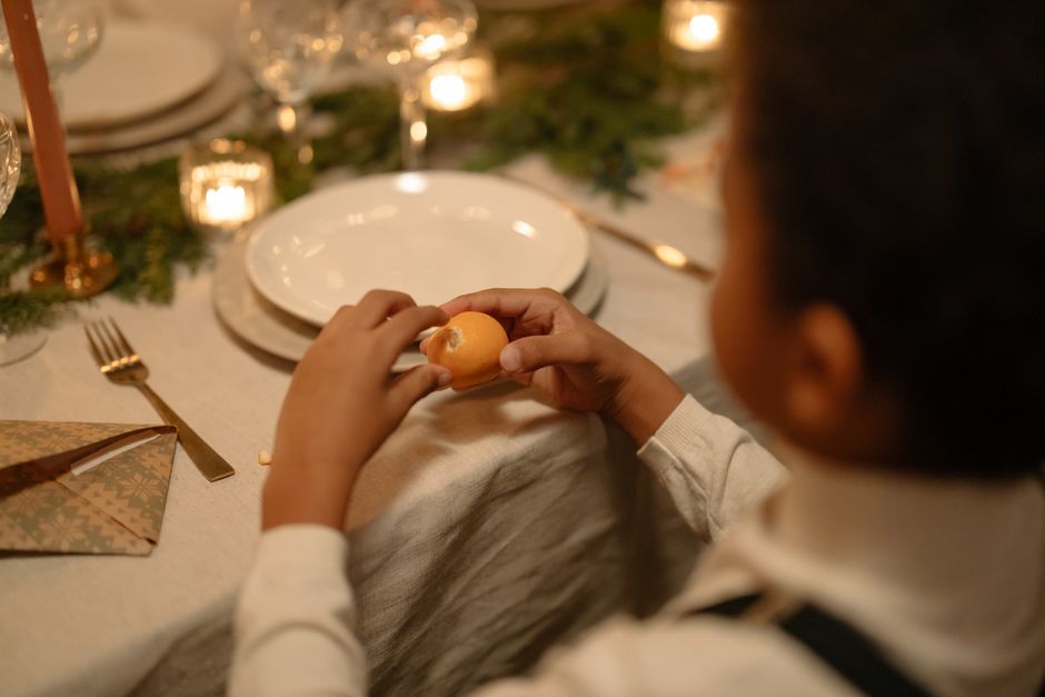 A child peeling a clementine at a beautifully set holiday dinner table.